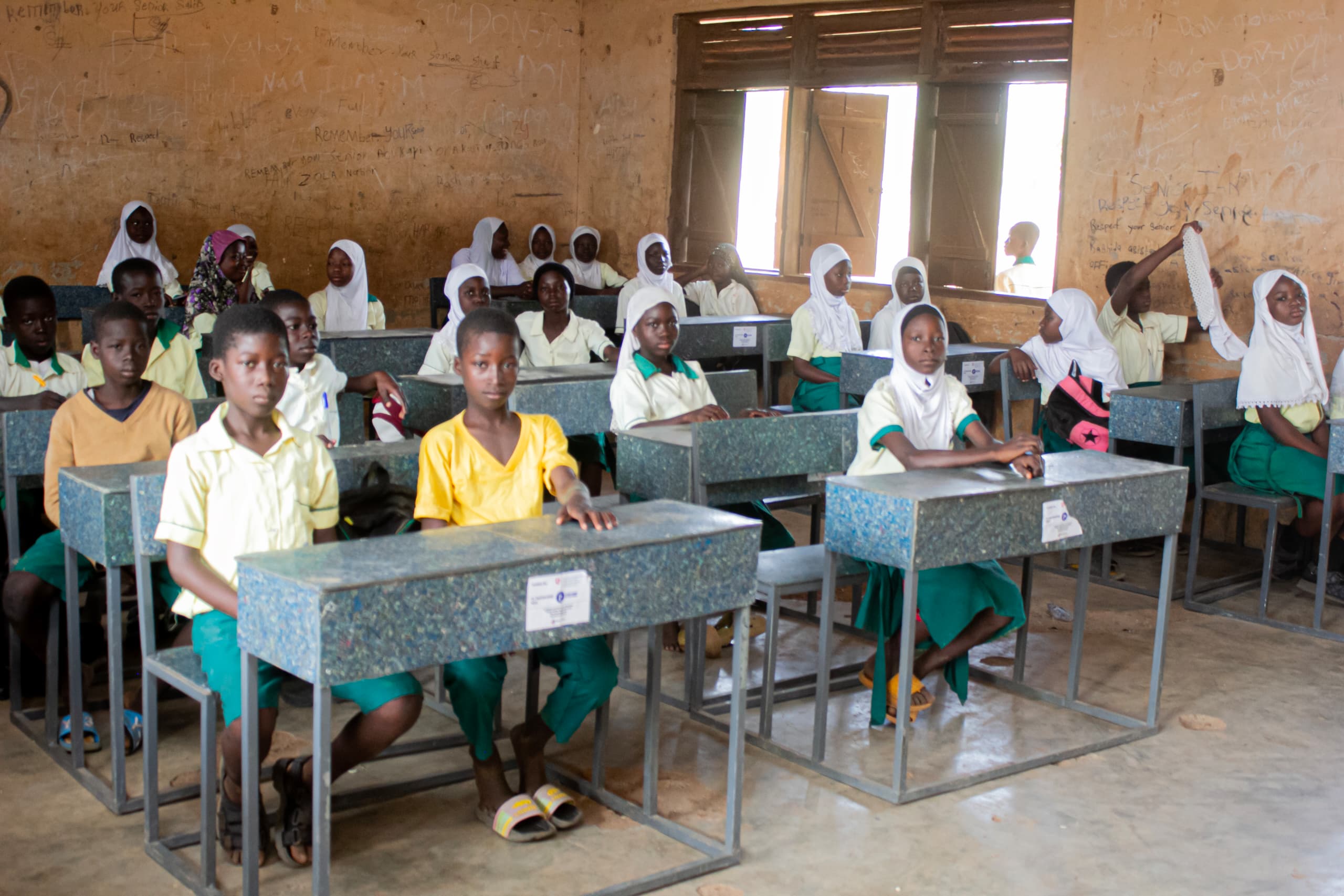 Students sitting in orderly rows at recycled plastic desks in a classroom